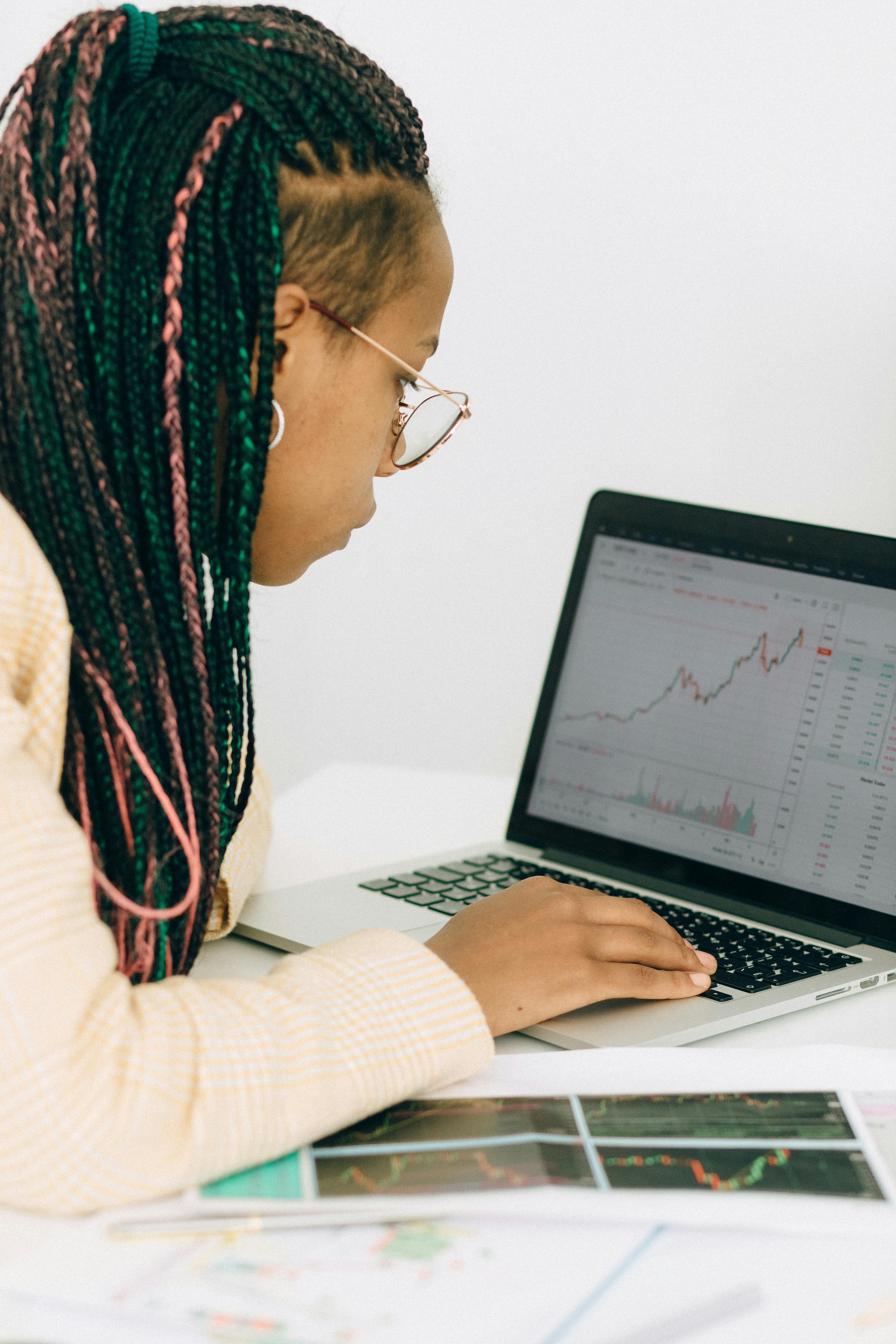 Woman monitoring financial charts on laptop and smartphone